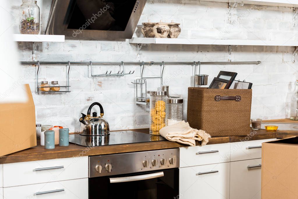 interior of modern kitchen with cardboard boxes during relocation at new home