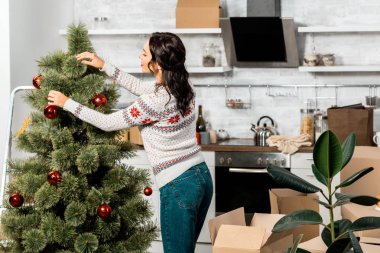 Dikiz genç kadının evde mutfak baubles tarafından Noel ağacı süsleme 
