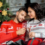 Couple ceebrating et cliquetis par des verres de champagne sur canapé près de l'arbre de Noël à la maison