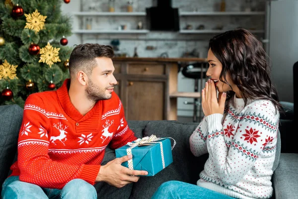 Guapo Joven Regalando Navidad Presente Novia Sorprendida Haciendo Gestos Con —  Fotos de Stock