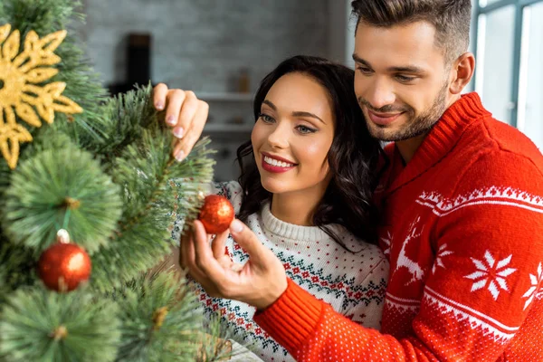 Smiling Young Couple Decorating Christmas Tree Baubles Home — Free Stock Photo