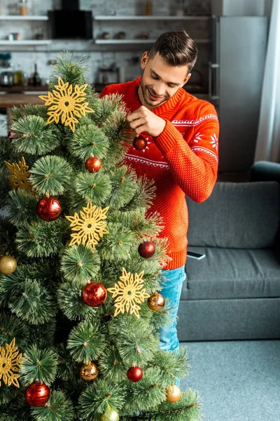 Happy Young Man Decorating Christmas Tree Baubles Home — Free Stock Photo