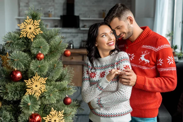 Zâmbind Cuplu Tânăr Îmbrățișându Uitându Unul Celălalt Lângă Pomul Crăciun — Fotografie, imagine de stoc
