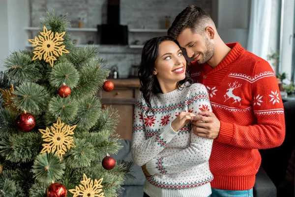 Glimlachend Jong Koppel Omarmen Kijken Elkaar Buurt Van Kerstboom Thuis — Stockfoto