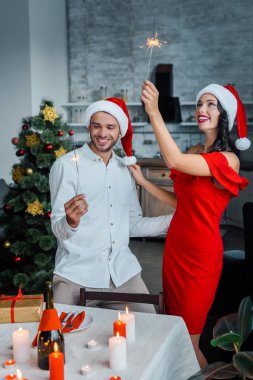 mutlu genç çift bengal ışıkları ile evde kutlama Noel şapka içinde