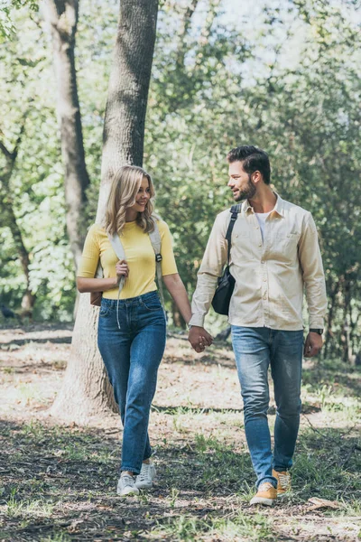Sorrindo Jovem Casal Com Mochilas Mãos Dadas Enquanto Caminhava Parque — Fotografia de Stock