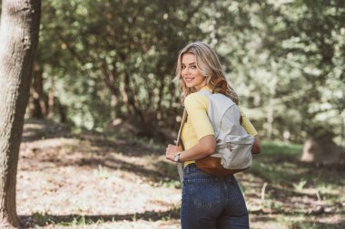 arkadan görünüşü güzel gülümseyen kadın parkta sırt çantası ile