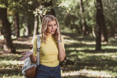 Park Smartphone cep telefonu ile konuşurken sırt çantası olan duygusal kadın portresi