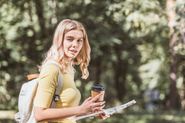 Genç Sarışın kadın kahve ile gidip gazete Park seyahat yan görünüm