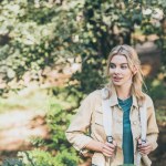 Portrait of young pensive female tourist with backpack in park