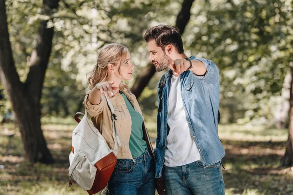 笑みを浮かべて スタイリッシュなカップルが秋の公園でカメラを指差し — ストック写真