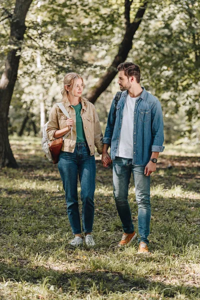 秋の公園でデート中に手を繋いでいるスタイリッシュなカップル  — 無料ストックフォト