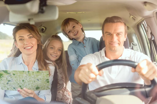 Onnellinen Nuori Perhe Katselee Kameraa Matkustaessaan Autolla — kuvapankkivalokuva