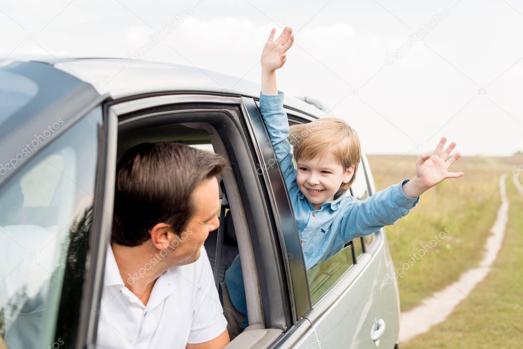 happy father and son riding car on nature together