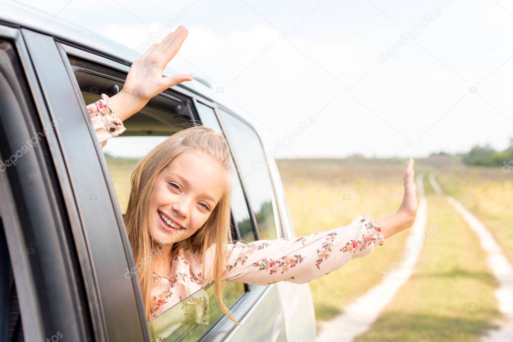 celebrating little child looking out of car window while riding by field