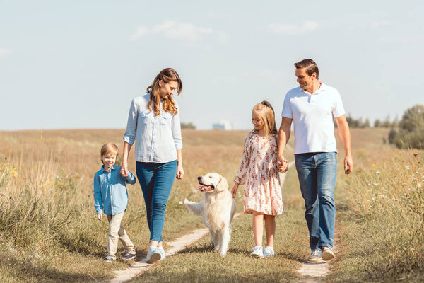 happy young family with retriever dog spending time together in field
