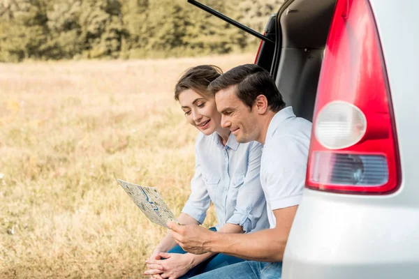 Happy Adult Couple Sitting Car Trunk Looking Map — Free Stock Photo