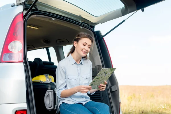 Smiling Adult Woman Sitting Car Trunk Looking Map Field — Free Stock Photo