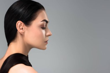 profile of beautiful young brunette woman looking away isolated on grey clipart