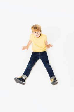 oturan ve üzerinde beyaz izole kamera gülümseyen güzel mutlu küçük çocuğun yüksek açılı görünüş