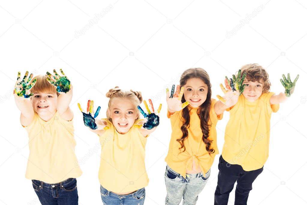 high angle view of adorable happy kids showing hands in paint and smiling at camera isolated on white