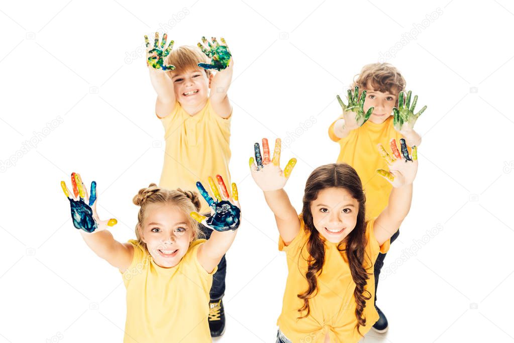 high angle view of happy children showing hands in paint and smiling at camera isolated on white