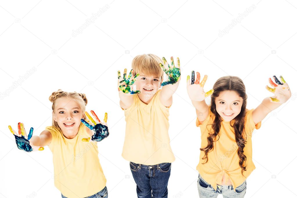 high angle view of happy kids showing hands in paint and smiling at camera isolated on white