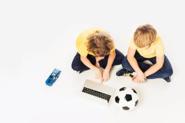 iki küçük çocuk üzerinde beyaz izole oyuncaklar ile otururken dizüstü kullanarak havai görünümü