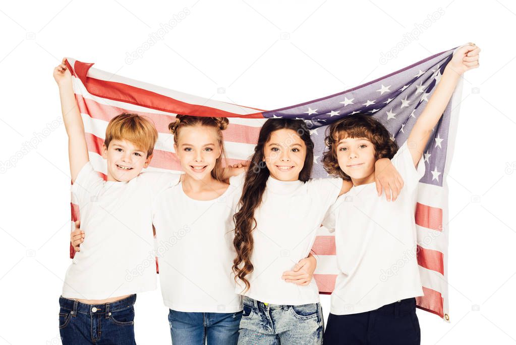 smiling adorable children standing under american flag and looking at camera isolated on white