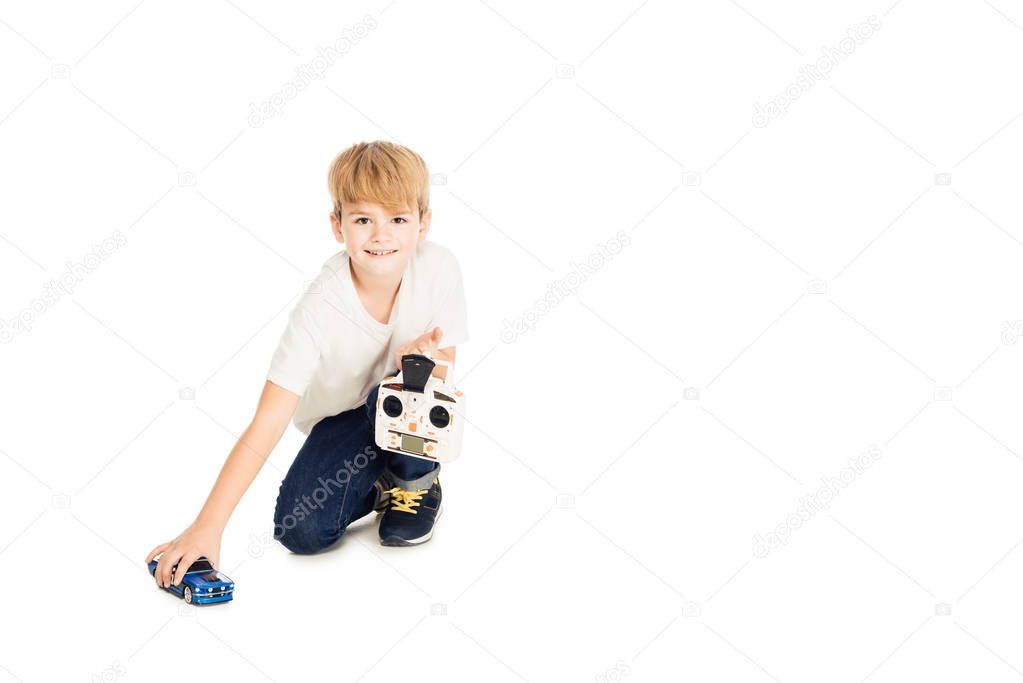 adorable boy playing with radio controlled car isolated on white and looking at camera