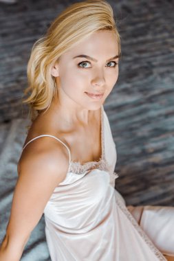 oturma ve yatak odasında kamera gülümseyen güzel sarışın kızın yüksek açılı görünüş