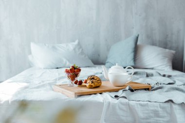 kruvasan, çilek ve çay yatakta ahşap tepsi