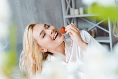 çekici kadın kapalı gözlerle sabah yatakta çilek yeme pijama