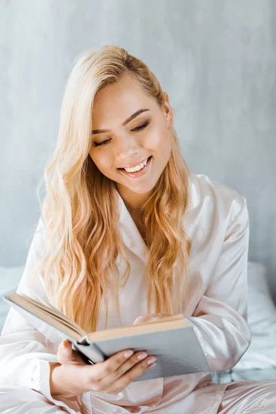 Hermosa Joven Sonriente Pijama Leyendo Libro Dormitorio — Foto de stock gratis