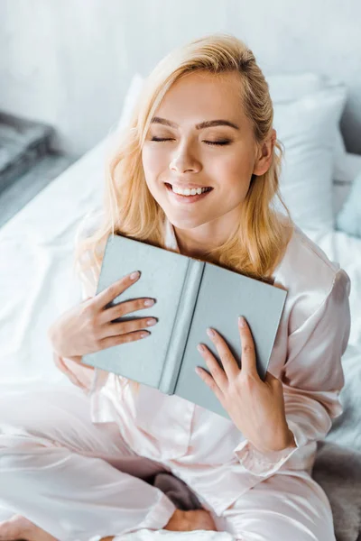 Hermosa Joven Sonriente Con Los Ojos Cerrados Sentado Cama Sosteniendo — Foto de Stock