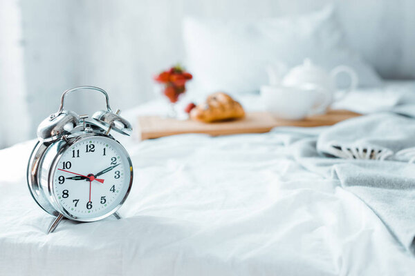 close-up view of alarm clock and tasty breakfast on bed