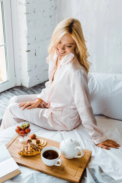 朝のベッドでの朝食で木製のトレイを見て美しい女性の笑顔ハイアングル — ストック写真