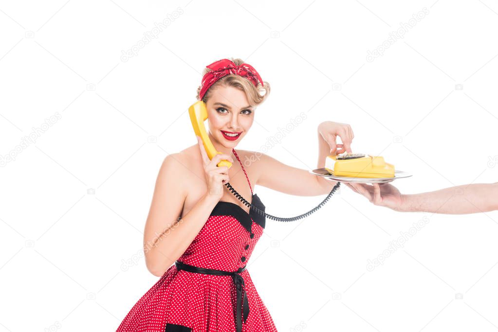 young pin up woman dialing phone number of retro telephone on serving tray in male hand isolated on white