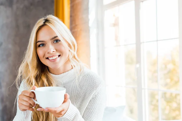 Cheerful Beautiful Woman Sweater Holding Cup Coffee Looking Camera Bedroom — Stock Photo, Image
