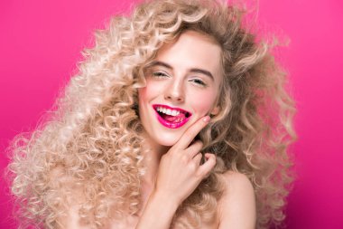 portrait of beautiful young woman with long curly hair smiling at camera isolated on pink clipart