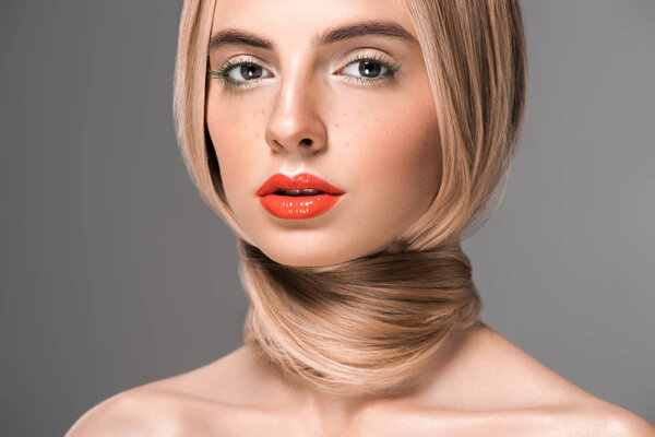 привлекательная голая девушка с длинными волосами, обернутыми вокруг шеи, смотрящая на камеру, изолированную на сером
