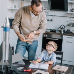 Père et fils lisant la littérature pour modéliser fusée à la maison