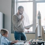 Pensive father and son modeling rocket at home