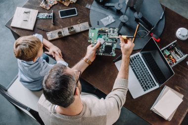 high angle view of father and son soldering circuit board with soldering iron at home clipart