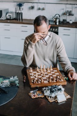 yorgun adam satranç oynamaktan ve burun köprüsü evde dokunmadan yüksek açılı görünüş
