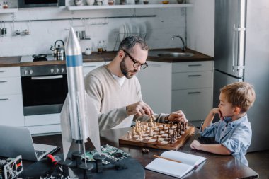 Baba ve sevimli küçük oğul evde birlikte satranç 