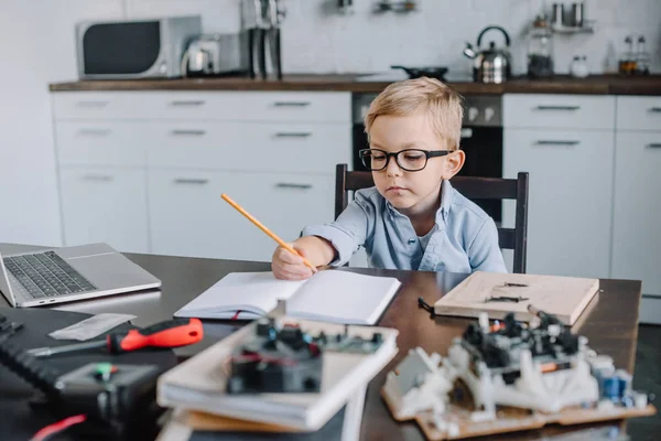 Menino Adorável Escrever Algo Para Notebook Mesa Casa — Fotografia de Stock Grátis