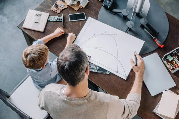 Overhead View Father Son Looking Blueprint Modeling Rocket Home — Stock Photo, Image