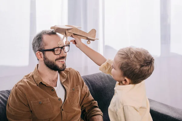 愉快的父亲和儿子玩木制玩具飞机在家里 — 图库照片
