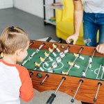 Visão parcial do pai e do filho jogando futebol de mesa juntos em casa